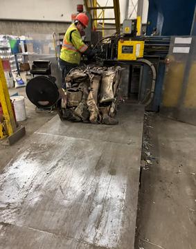 Worker Operating Metal Compactor at Scrap Recycling Facility